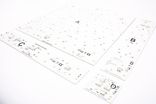 Four white LED circuit boards of different sizes are laid out on a white surface. Each board is labeled A, B, C, and D, and features several small electronic components and LED lights. The boards also display various technical specifications and certification marks.