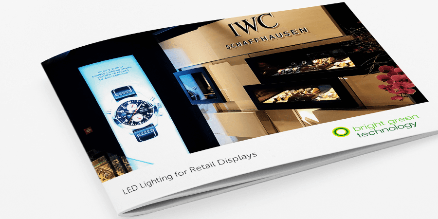 A brochure showcasing LED lighting for retail displays is open, featuring images of luxury watch displays and the text "IWC Schaffhausen." The brochure has the logo and name "Bright Green Technology" on the bottom right corner.