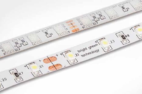 Close-up of two LED strip lights parallel to each other. The strips feature various electronic components, including LED bulbs and resistors. One strip has the text "bright green technology" printed on it, along with numerical identifiers for the components.