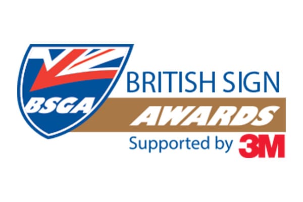 Logo for the British Sign Awards supported by 3M. It features a shield with the letters "BSGA" and a stylized British flag. The text "British Sign Awards" is written to the right, with "Supported by 3M" below.