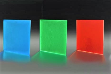 Three translucent acrylic sheets, standing upright side by side, are illuminated by built-in LEDs. These custom-manufactured light panels emit a vivid glow in blue, green, and red from left to right. Ideal for architectural features, they create a stunning display against a dark background.