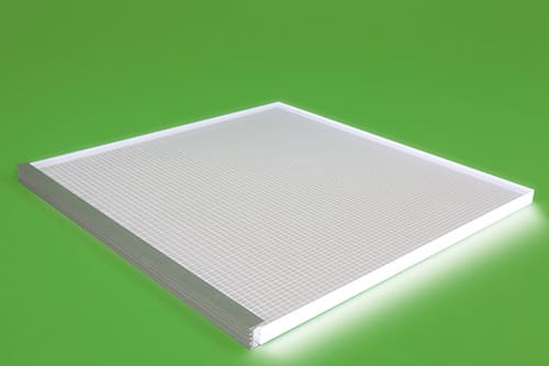 A square LED panel light with a grid-like surface pattern is placed against a bright green background. The panel has illuminated edges, highlighting its thickness and design.